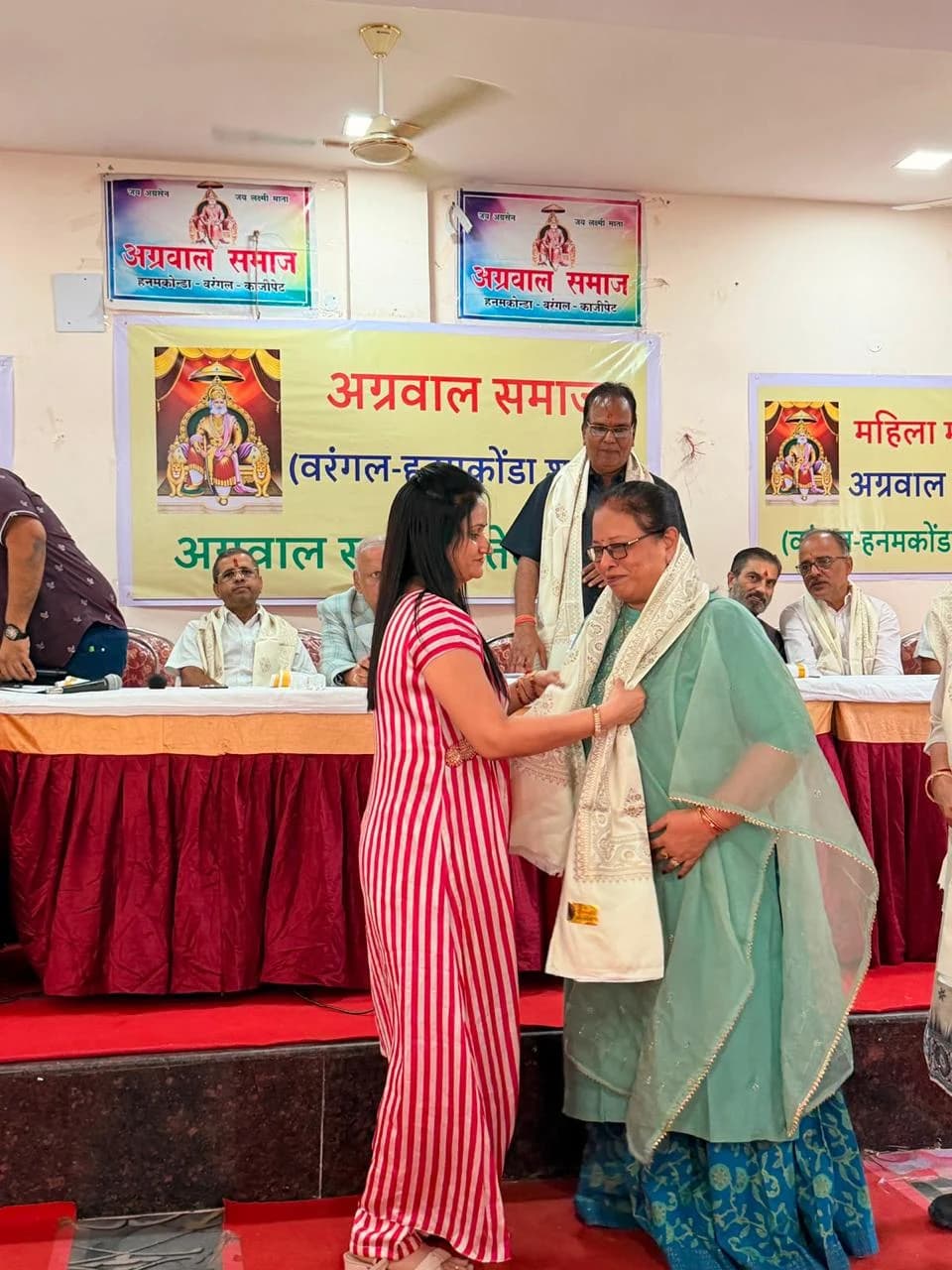 A participant is welcomed with a ceremonial shawl.